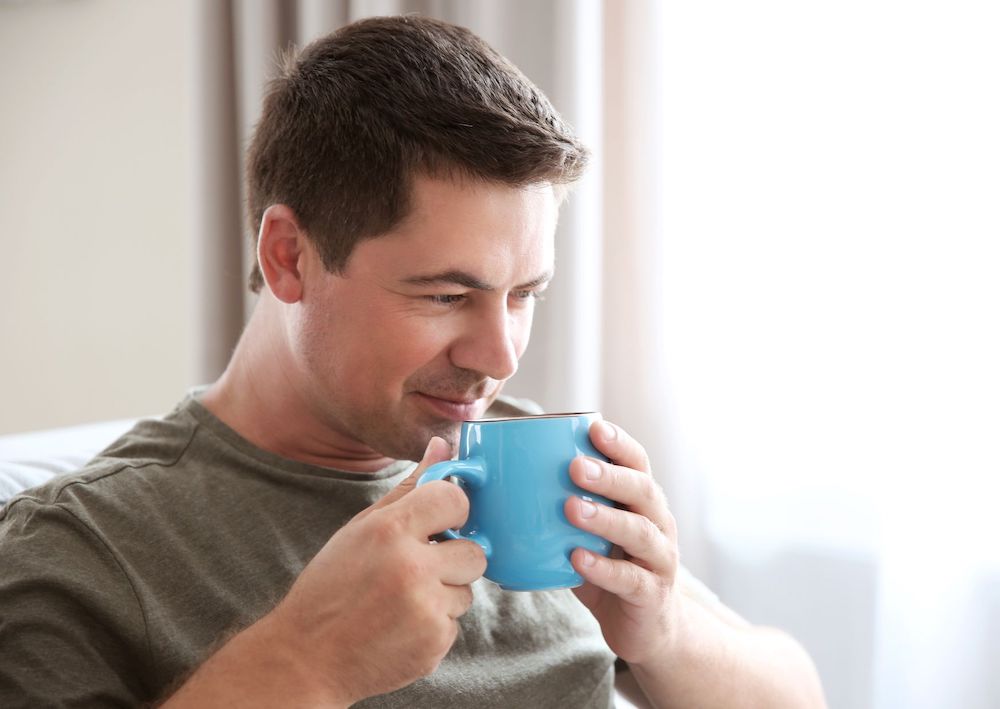 lelaki menghirup secangkir kopi