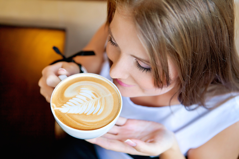 seorang wanita sedang meminum secangkir latte