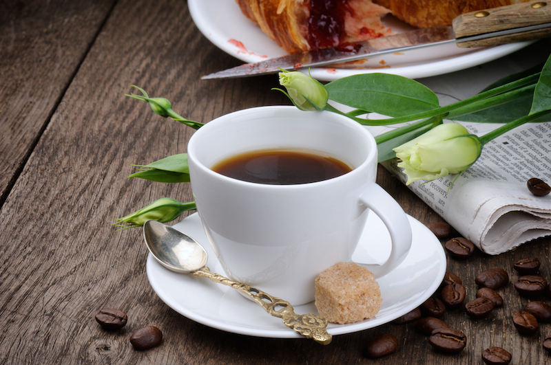 secangkir kopi hitam dengan gula merah padat di pinggir piring cangkir