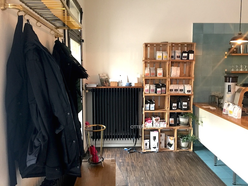 Rak penuh kopi dan gantungan jaket tersusun rapi,