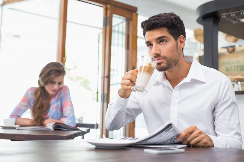 pria minum kopi sambil membaca koran
