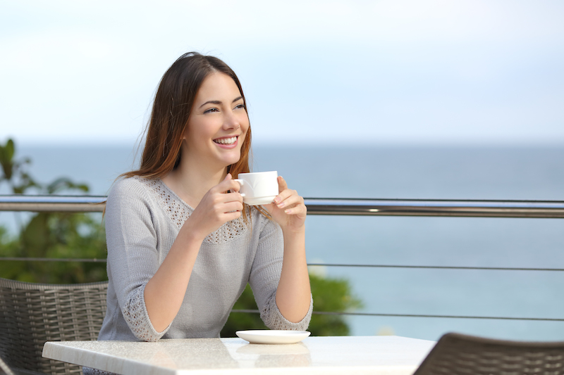 perempuan menikmati pemandangan sambil minum secangkir kopi