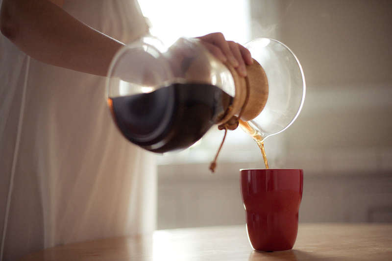menuang kopi ke cangkir kopi dari alat kopi chemex