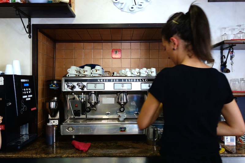 seorang barista sedang menyiapkan kopi dengan mesin espresso
