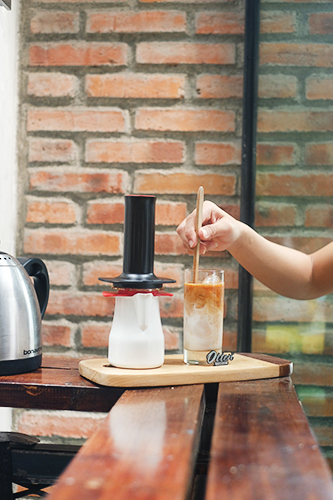 mengaduk kopi susu dengan sendok kayu