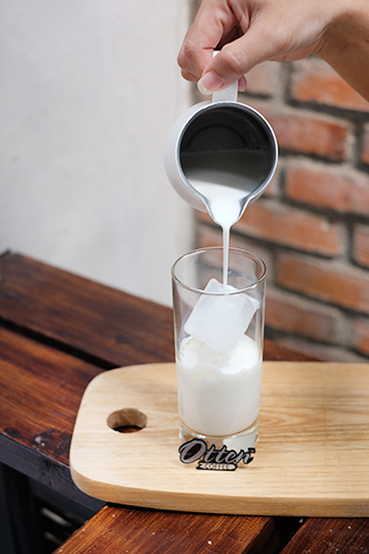menuang susu ke gelas kopi berisi es batu
