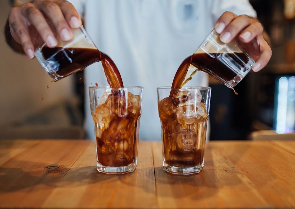 menuangkan espresso ke gelas berisi es batu