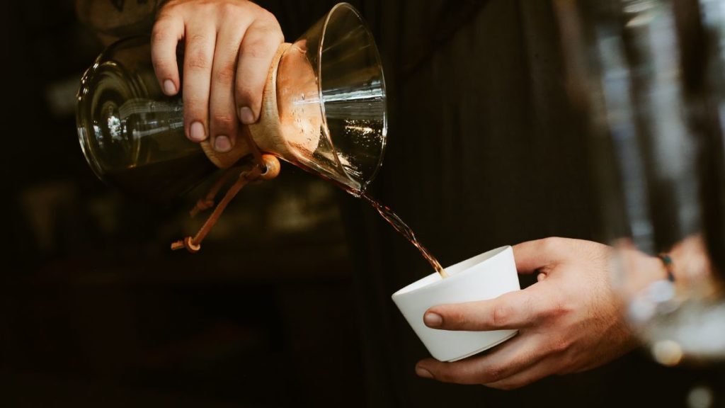 menuang kopi dari alat kopi chemex ke cangkir kopi